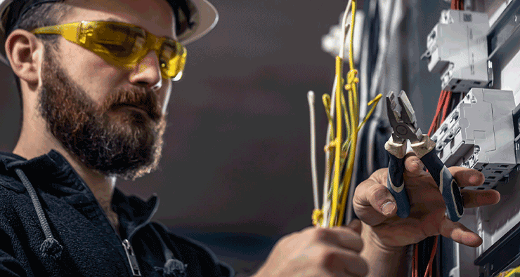 Um homem com capacete e óculos de segurança trabalhando em equipamentos elétricos