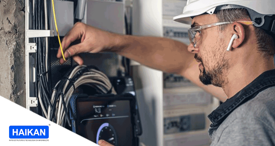 Um homem com capacete e óculos de segurança trabalhando em um painel elétrico