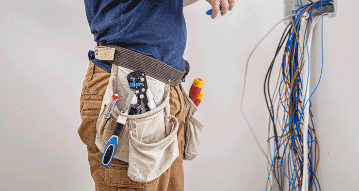 Um homem de camisa azul está segurando um cinto de ferramentas