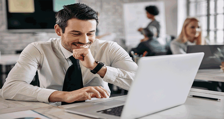 Homem trabalhando sorridente em frente ao seu notebook